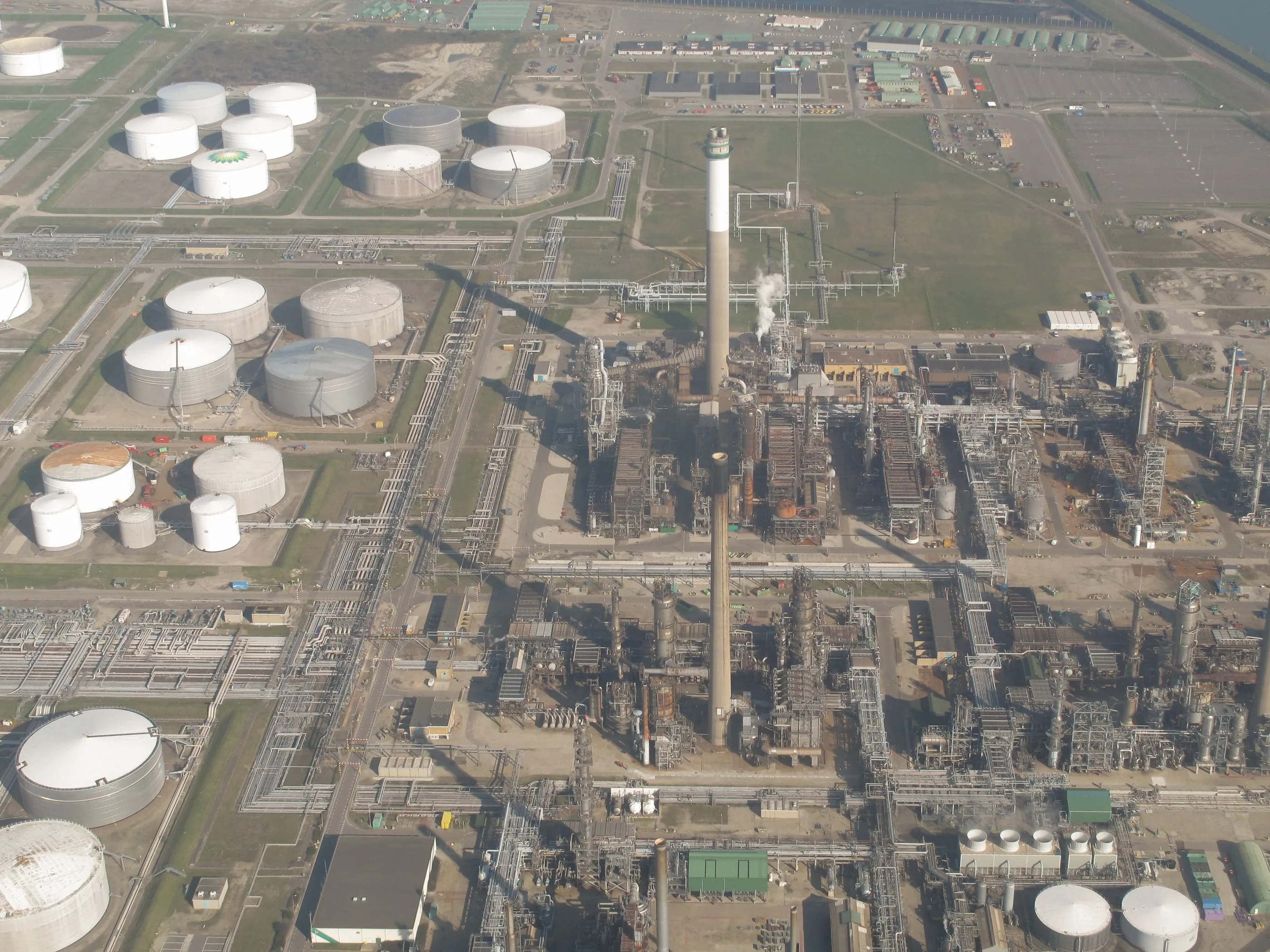 An oil refinery and rows of storage tanks seen from the air.