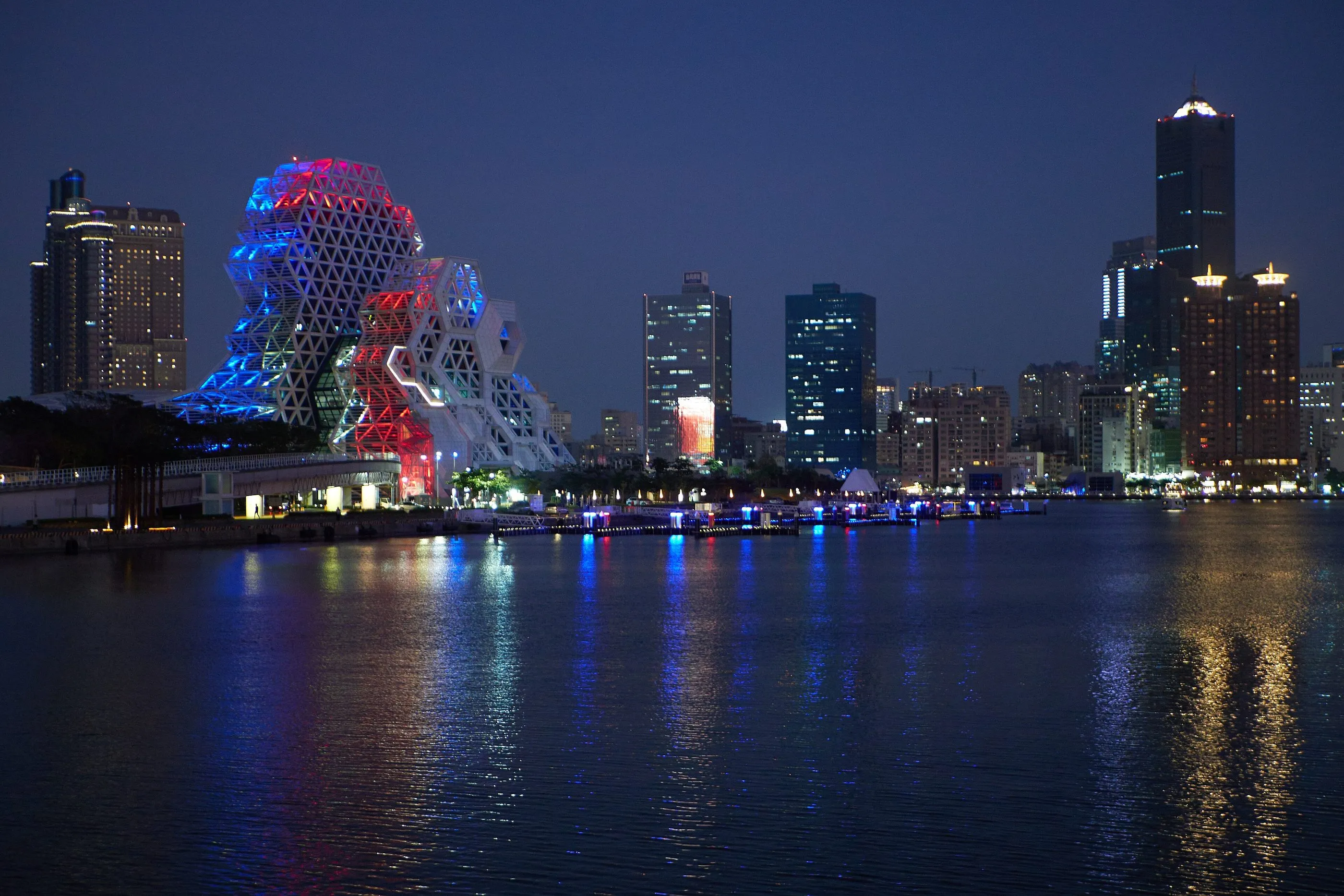 Kaohsiung harbour at night, with the city lights reflected in the water.